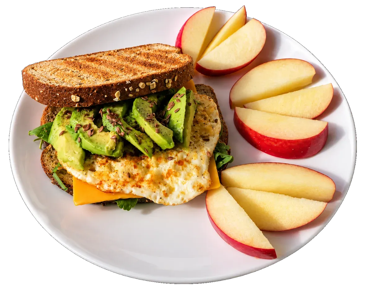 An avocado and egg sandwich on a plate with red apple wedges.